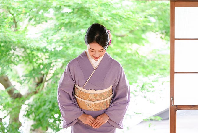 Una mujer en kimono saludando