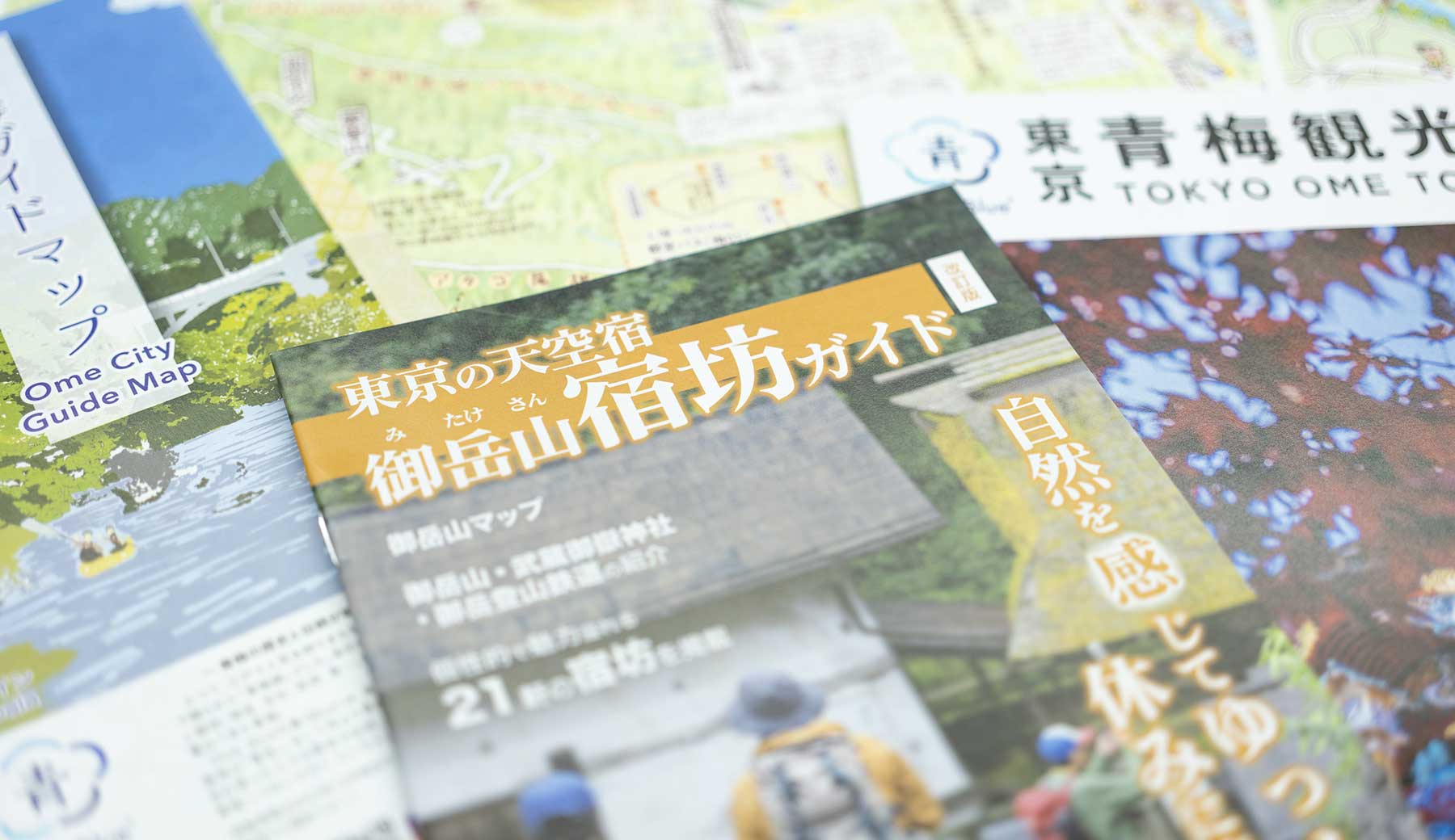 青梅市観光協会が発行する、「東京の天空宿 御岳山宿坊ガイド」などの観光パンフレットが机に置かれた写真